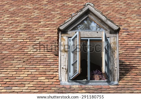 open window in an old dormer made of wood on a roof with historic beaver tail tiles, copy space