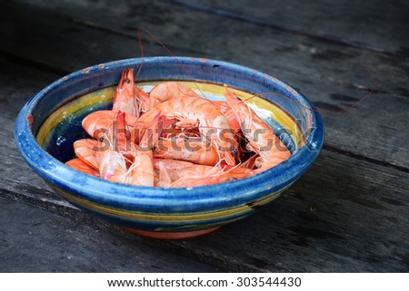 Fresh boiled tiger shrimps in a terracotta bowl on rustic dark wood, space for your design