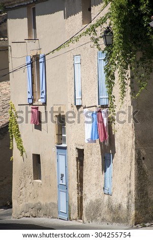 typical house in south France with blue shutters and drying laundry outside the windows in the old mountain village of Cadenet, Provence, Luberon Massif