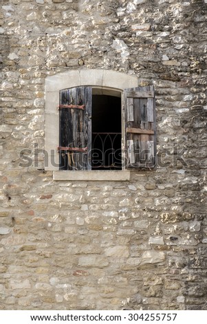 ancient building made of natural stone with a window and half-open shutters of wood, copy space in the wall, Cucuron, Provence, France, region Luberon