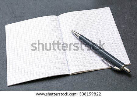 ballpoint pens and a blank notebook with graph paper on a gray blotting pad, copy space