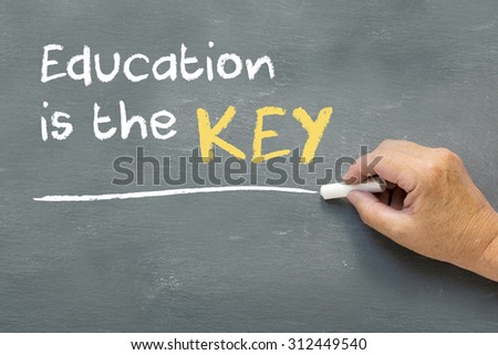 Hand on a chalkboard with the words Education is the key. Education class concept showing teacher hand writing on the blackboard.