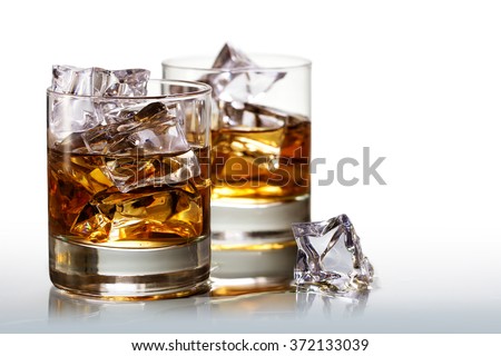 Two glasses of scotch whiskey with ice cubes, background fades to white, copy space