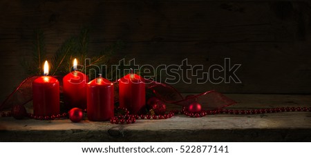Red candles, two of them burning on the second advent, christmas decoration with baubles on a rustic board, dark wooden background with copy space, panorama banner or website header, selective focus