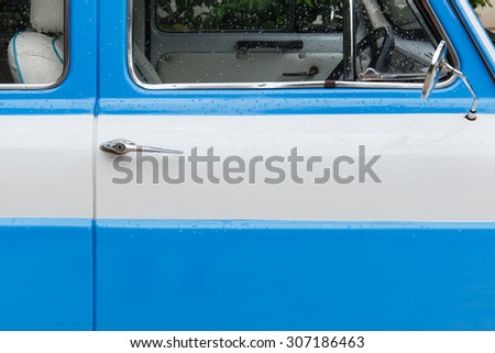 Car door of soft blue and white classic car.