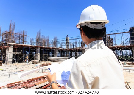 Engineer looking plant at construction site with blue sky background.