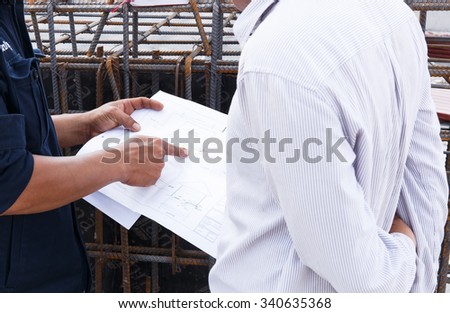 Engineer holding and point plan on construction site.
