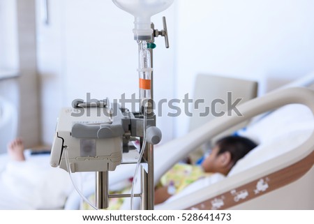 Close up IV set and blurry illness asian boy sleeping on hospital bed.Medical equipment concept.
