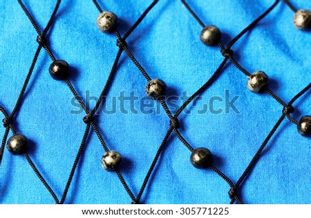 Black  mesh with wood bullets on blue material background