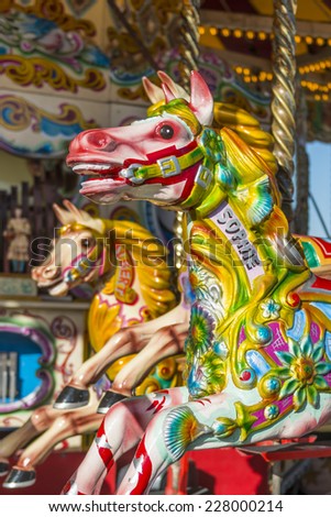 BRIGHTON, UK - OCTOBER 26: Brightly coloured carousel horses on a fairground ride at Brighton\'s Palace Pier with a de-focused background shown on October 26, 2014 in Brighton, UK