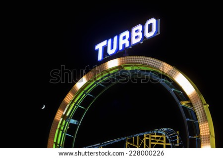 BRIGHTON, UK - OCTOBER 28: Illuminated \'Turbo\' sign on top of a roller coaster loop at night shown on October 28, 2014 in Brighton, UK
