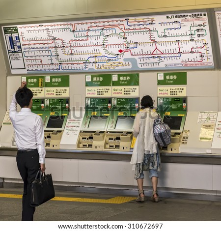 TOKYO, JAPAN - AUGUST 5: A confused passenger approaching the railway station ticket machines in Tokyo with the system map above shown on August 5, 2015 in Tokyo, Japan