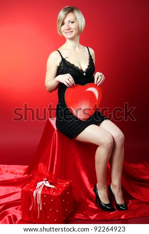 Young beautiful blonde girl hugs a big heart. Feast of St. Valentine\'s Day.