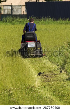 worker mows the lawn tractor