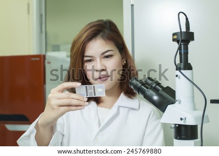 Young female tech or Scientist using a microscope and check result of sample on glass in a laboratory