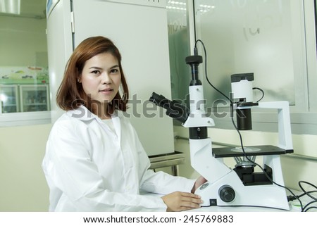 Young female tech or Scientist using a microscope in a laboratory