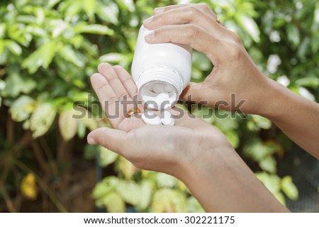 hand of doctor holding Many pills and tablets and medicine out of a bottle on nature background