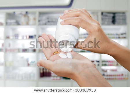 hand of doctor holding Many pills and tablets and medicine out of a bottle on medicine cabinet and store medicine and pharmacy drugstore