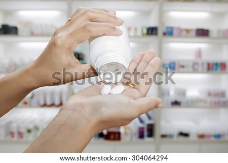hand of doctor holding Many pills and tablets and medicine out of a bottle on medicine cabinet and store medicine and pharmacy drugstore