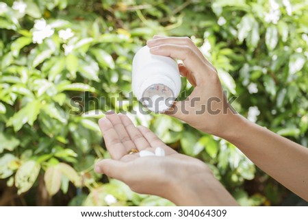 hand of doctor holding Many pills and tablets and medicine out of a bottle on nature background