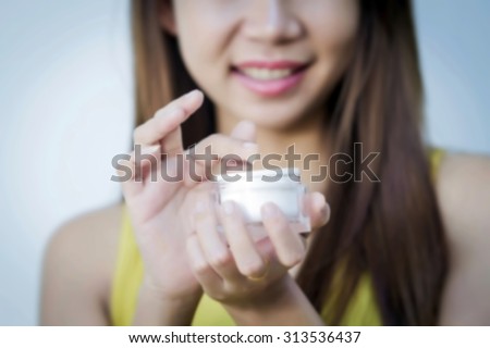 Blurry A beautiful woman asia using a skin care product, moisturizer or lotion and Skincare taking care of her dry complexion. Moisturizing cream in female hands .