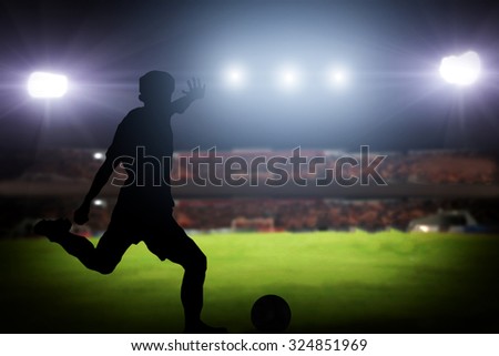 silhouette of a player shooting football on goal. Lights on the football stadium at night.