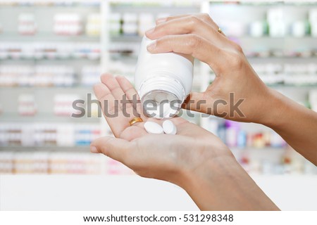 hand of doctor holding medicine bottle on medicine cabinet and store medicine and pharmacy drugstore