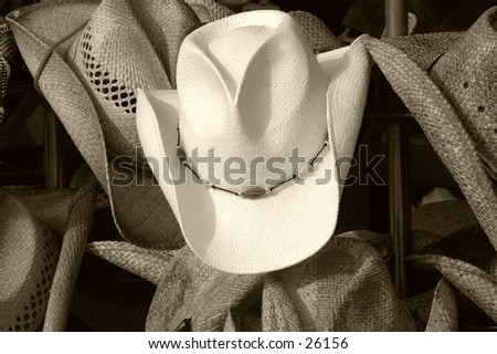 Full frame of cowboy hats. Central focus on the lone white hat in the middle