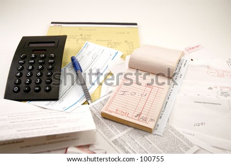 Calculator, legal pad, receipt book, paycheck and a pile of bills