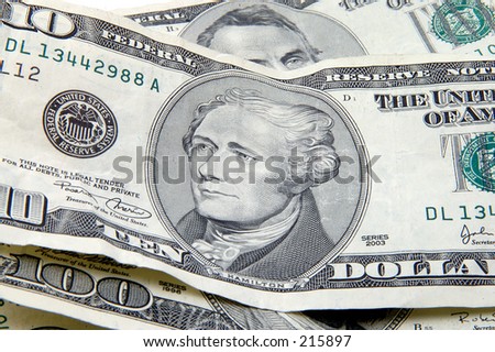 Close up of Hamilton on a ten dollar bill surounded by other bills