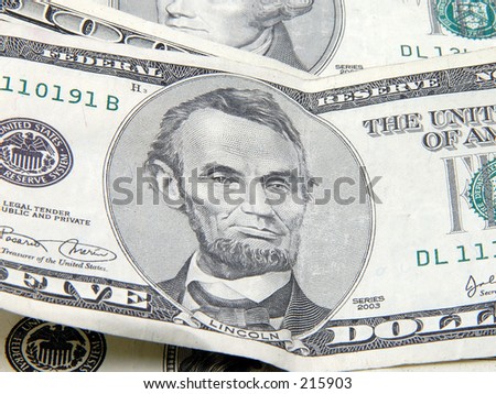 Close up of Lincoln on a five dollar bill suround by other bills