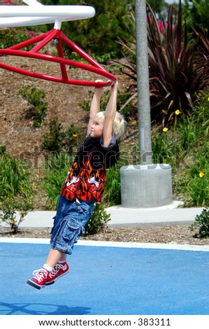 Blond boy child in a rock and roll flame shirt playing in the park playground