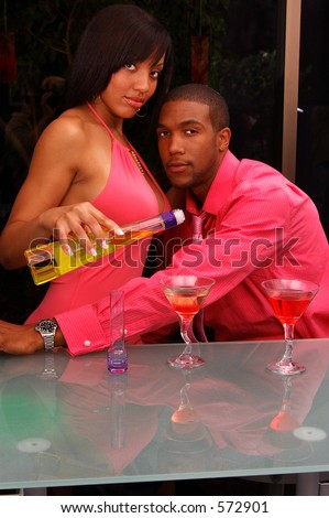African American couple in a martini bar.Woman pouring a drink