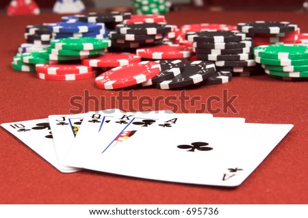 One of the highest hands in poker a Clubs Royal Flush on a red felt gaming table with a poker jackpot in the background