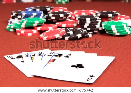 One of the highest hands in poker a Clubs Royal Flush on a red felt gaming table with a no limit jackpot in the background