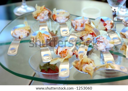 Gourmet banquet table featuring chicken and pasta canapÃ©s in individual serving spoons.