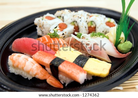 Combination sushi plate with a spicy California sushi roll and salmon,tuna,whitefish,yellowtail,sweet egg, sweet shrimp and crab sushi garnished with wasabi and pickled ginger