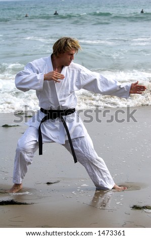 Man with a black belt working out on the beach.