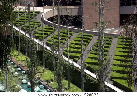 A modernistic walkway lined with maze like shrubs leading to a Southern California corporate office building
