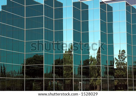 Modern corporate office building in Southern California built of reflective blue glass. Nicely landscaped with grass and evergreen trees