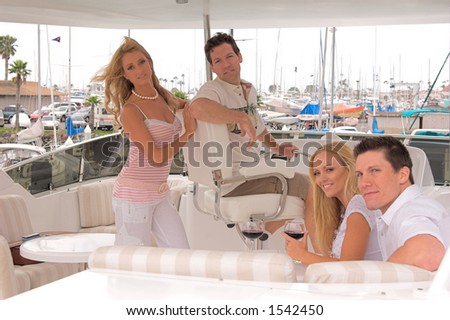 Two young couples on the fly bridge of a private yacht, laughing and having a good time as they pull out of the harbor