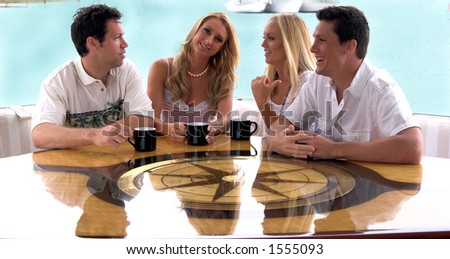 Two young couples share a cup of coffee on the aft deck of a private yacht after a long day at sea