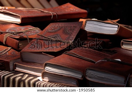 A pile of hand tooled leather bound journals on a library table