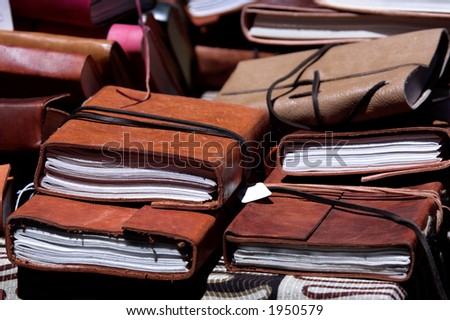 A pile of hand tooled leather bound journals on a library table