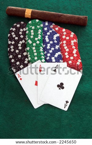 Three aces laying on a stack of casino chips with a nice cigar on a green felt table