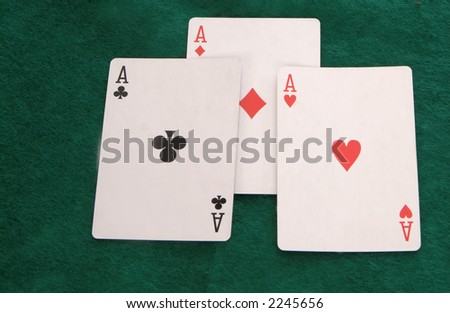 Three aces laying on a cigar on a green felt table