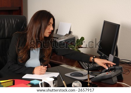 Female executive reaching to answer the phone at her desk