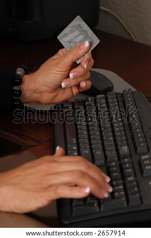 Close up detail of a business womans hands holding a credit card and making a purchase on line
