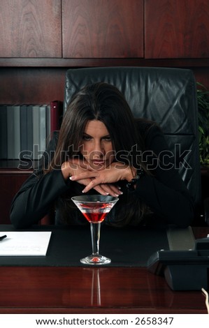 Business woman in an executive office sits with her hands folded under her chin and stares wistfully at the Martin on her desk