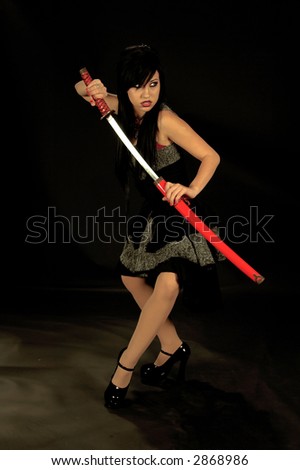 Beautiful raven haired Gothic Vampire Slayer in a black and grey dress slipping through the night with a samurai  sword